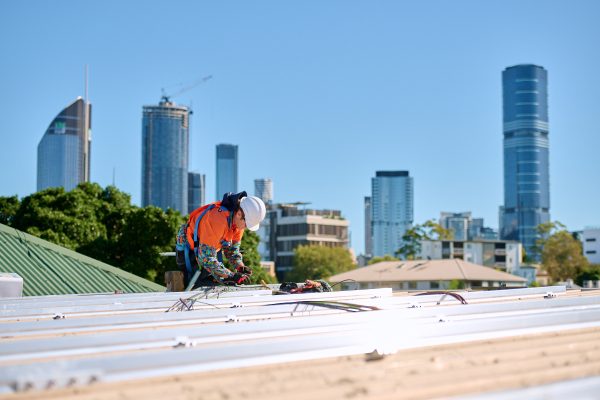 Qualified renewable energy installers from Gardel Electrical & Solar working on the Pineapple Hotel's transition to green energy with Brisbane city in the background